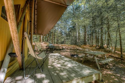 a porch of a cabin with a bench and a picnic table at Huttopia White Mountains in Albany