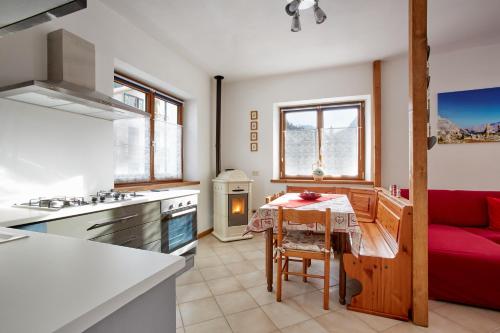 a kitchen and living room with a red couch and a table at Dolomiti Openspace Free Parking in San Nicolò di Comelico