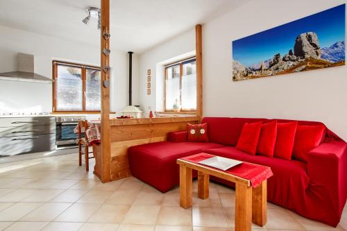 a living room with a red couch and a kitchen at Dolomiti Openspace Free Parking in San Nicolò di Comelico