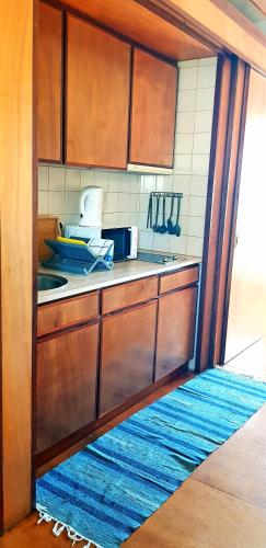 a kitchen with wooden cabinets and a blue rug at Palácio da Portela III in Coimbra