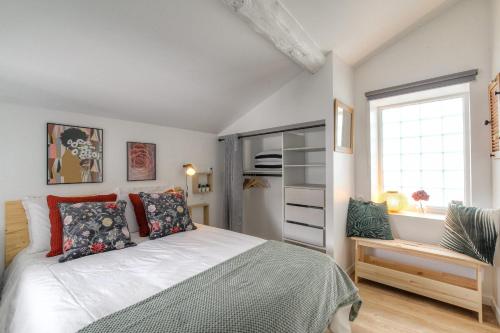 une chambre avec un lit avec des oreillers et une fenêtre dans l'établissement Le chaleureux et cosy proche Lyon, à Les Rivages