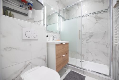 een witte badkamer met een douche en een toilet bij Stunning flat in Paris in Parijs