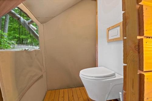 a bathroom with a toilet and a window at Huttopia Lake George - Adirondacks in Lake Luzerne
