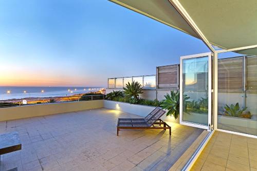a balcony with a bench and a view of the ocean at Horizon Bay 103 by HostAgents in Bloubergstrand