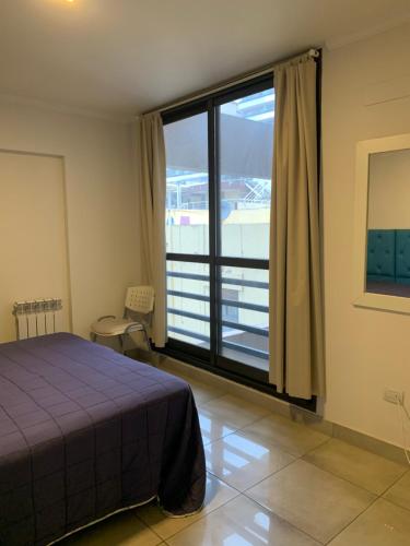 um quarto com uma cama e uma grande janela em Hermoso y calido depto centrico em Villa Carlos Paz