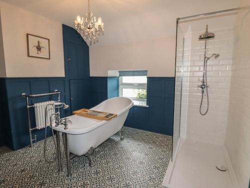 een badkamer met een bad en een glazen douche bij Wayside House in Craven Arms