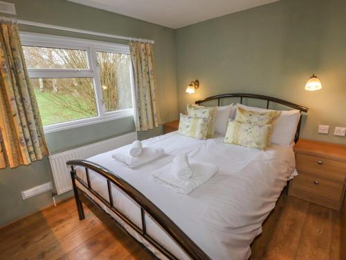 een slaapkamer met een bed met witte lakens en een raam bij Wayside Lodge in Craven Arms