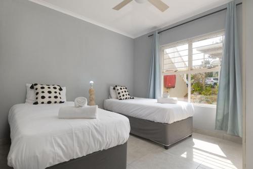 two beds in a room with a window at Kingston Estate 112 by HostAgents in Ballito