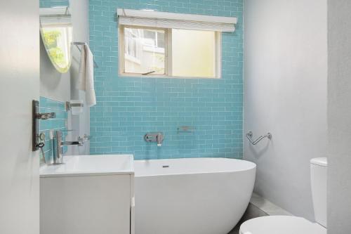 La salle de bains est pourvue d'un lavabo, de toilettes et de carrelage bleu. dans l'établissement Kingston Estate 112 by HostAgents, à Ballito