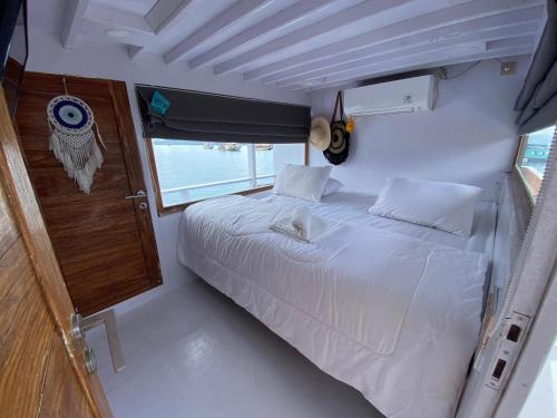 1 cama blanca grande en una habitación con ventana en William Komodo Travel, en Nggorang