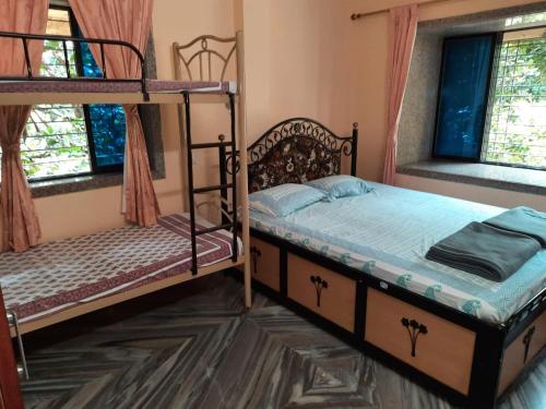 a bedroom with two bunk beds and two windows at Govindaashram in Bhogwe