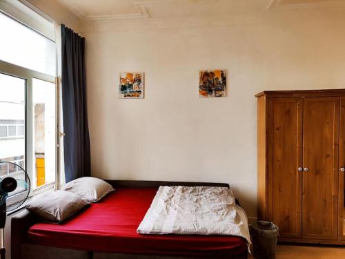 um quarto com uma cama vermelha e uma janela em Studio entier avec balcon - Tour et Taxis em Bruxelas