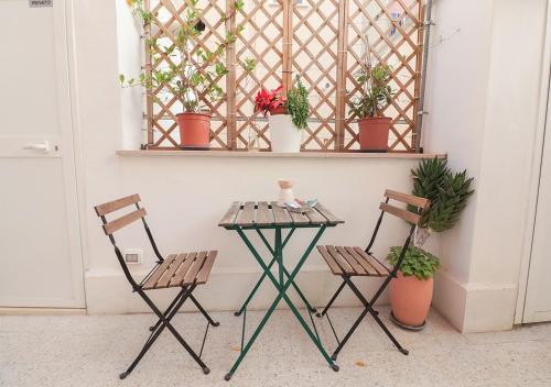 een tafel en stoelen naast een muur met potplanten bij Bed and Breakfast il Pesciolino in Trani