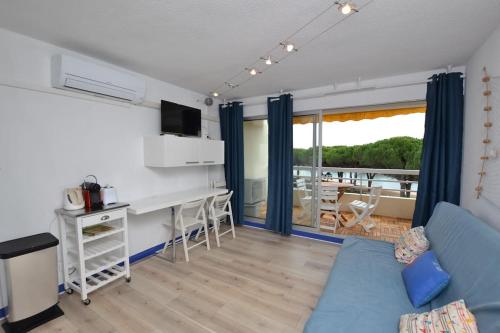 ein Wohnzimmer mit einem blauen Sofa und einem Balkon in der Unterkunft La lagune vue canal et accès mer in Le Grau-du-Roi