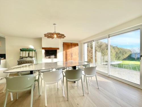 une cuisine avec une table et des chaises ainsi qu'une grande fenêtre dans l'établissement VILLA BREIZH RIVIERA - La plage au bout du jardin !, à La Forêt-Fouesnant