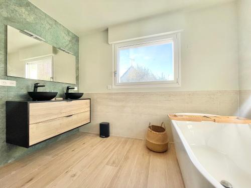 une salle de bain avec une baignoire, un lavabo et une fenêtre dans l'établissement VILLA BREIZH RIVIERA - La plage au bout du jardin !, à La Forêt-Fouesnant