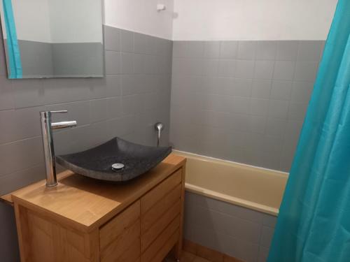 La salle de bains est pourvue d'un lavabo noir et d'une baignoire. dans l'établissement Le Temps d'une Pause au Calme, à Bouaye