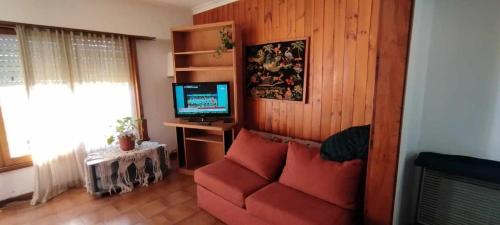 a living room with a red couch and a television at Casa, quincho, garage y parque.apta 10 personas in Mar del Plata