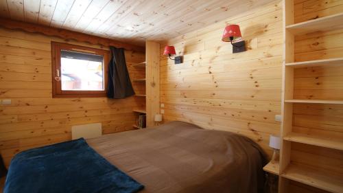 une chambre avec un lit dans une cabane en bois dans l'établissement SOLEIL DES ECRINS Puy Saint Vincent 1800 appart 4 pers refait neuf, à Puy-Saint-Vincent