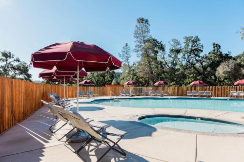 a swimming pool with two chairs and an umbrella at Huttopia Wine Country in Lower Lake