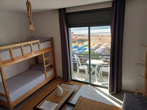 - une chambre avec des lits superposés et un balcon avec une table dans l'établissement Miramar Surf Anza, à Agadir