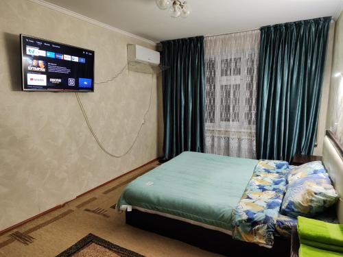 a bedroom with a bed and a tv on the wall at Квартира LUX, Lux apartment in Taraz