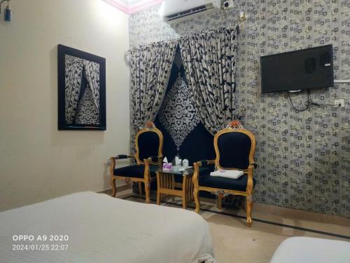 una camera da letto con due sedie, un tavolo e una TV di Hotel Eden Plus Lahore a Lahore
