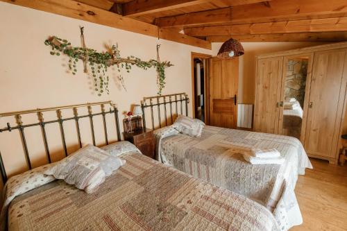 two beds in a room with wooden ceilings at Casa Rural El Cañico in Otero de Bodas