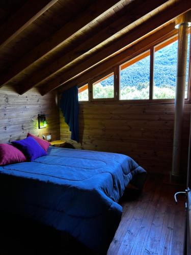 - une chambre avec un lit bleu dans une pièce dotée de fenêtres dans l'établissement Rio Manso cabaña km 18, à Río Villegas