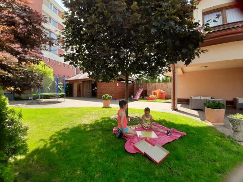 zwei Kinder sitzen auf dem Rasen im Hof in der Unterkunft B&B Penzión Magura in Bardejov