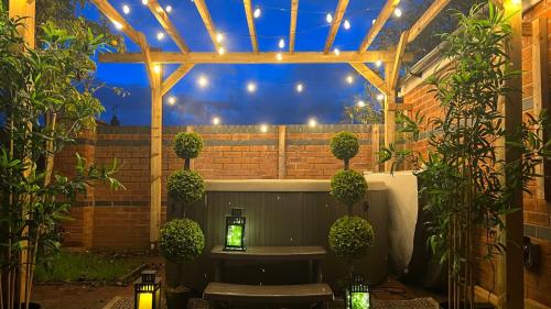 a patio with a pergola with lights and plants at The Cheshire Gathering - Sleeps up to 30 With Hot Tub in Chester