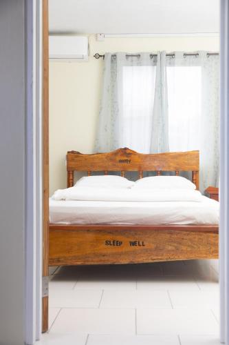 a bed with a wooden frame in a room at Happy Nest Dominica in Marigot