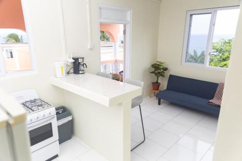 - une cuisine blanche avec cuisinière et canapé bleu dans l'établissement Happy Nest Dominica, à Marigot