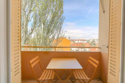 d'une table et de deux chaises sur un balcon avec une fenêtre. dans l'établissement Design et Convivial avec parking gratuit, à Villeurbanne