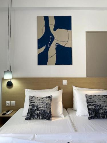 a bedroom with a white bed with a painting above it at VistaMare2 Double room-sea view in Koutsourás