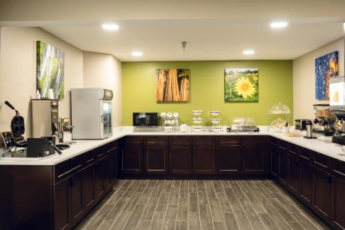 a large kitchen with brown cabinets and green walls at Sleep Inn & Suites Omaha Airport in Omaha