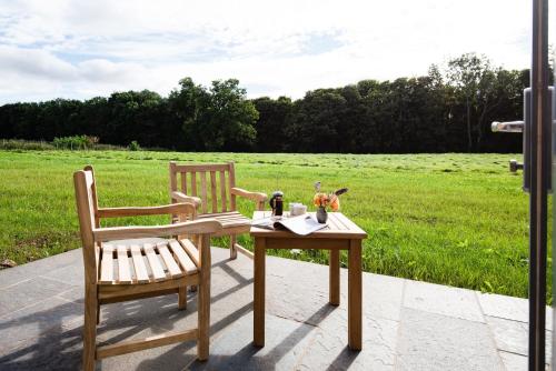 a table and two chairs sitting next to a field at Ploughman's Bothy at Papple Steading in East Linton