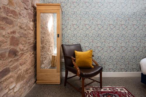 a chair with a yellow pillow in front of a mirror at Ploughman's Bothy at Papple Steading in East Linton