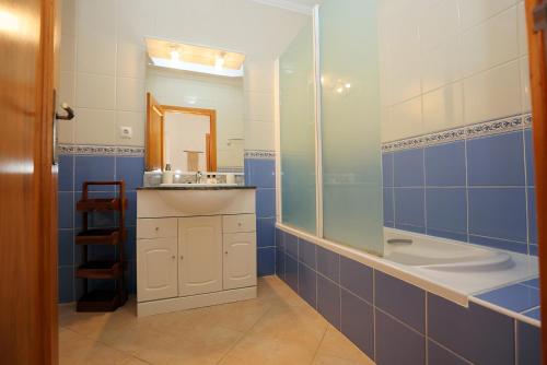 La salle de bains est pourvue de carrelage bleu, d'un lavabo et d'un miroir. dans l'établissement B95 - Casa Melo Apartment in Praia da Luz, à Luz
