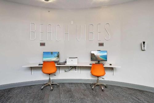 un bureau avec deux bureaux et deux chaises oranges dans l'établissement 1 BR Resort Condo Direct Oceanfront Wyndham Ocean Walk - Daytona Funland 1307, à Daytona Beach