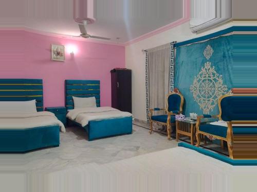 ラホールにあるHotel Eden Plus Lahoreのベッド2台と椅子2脚が備わる客室です。