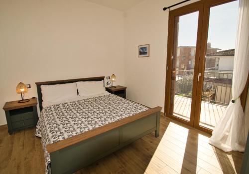 a bedroom with a bed and a large window at Dommu Livia in Lotzorai