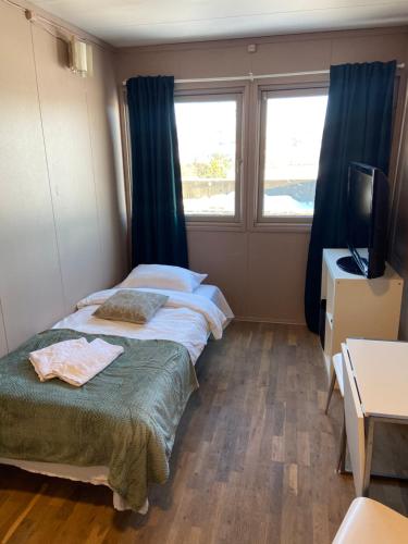 a bedroom with two beds and a tv and a window at Spørkel Landbruk in Lier
