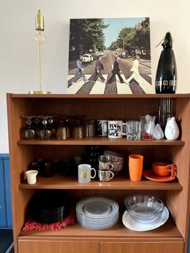 une étagère en bois avec des assiettes, des tasses et de la vaisselle dans l'établissement L'Atypique d'Orléans, à Orléans