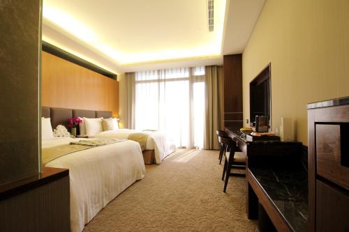 a hotel room with two beds and a desk at Fuli Hot Spring Resort in Yuchi