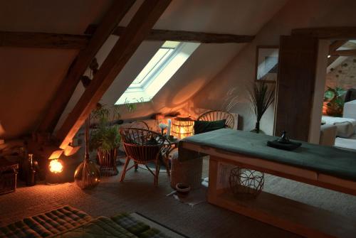 a attic room with a table and chairs and a window at Massages du Monde in Saint-Georges-sur-la-Prée
