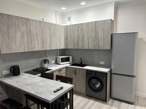 eine Küche mit einem Kühlschrank und einer Waschmaschine in der Unterkunft Апартамент in Bischkek
