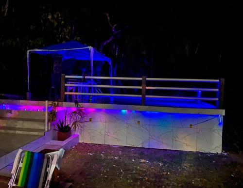 un banc avec des feux bleus et violets la nuit dans l'établissement Casa ariramba Mosqueiro, à Belém