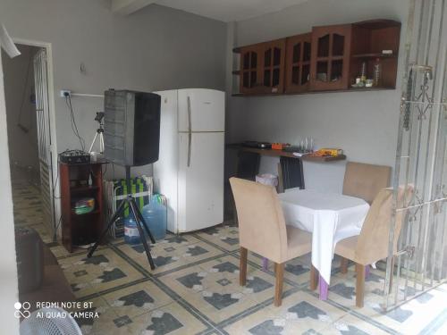 cocina con mesa, sillas y nevera en Casa ariramba Mosqueiro, en Belém