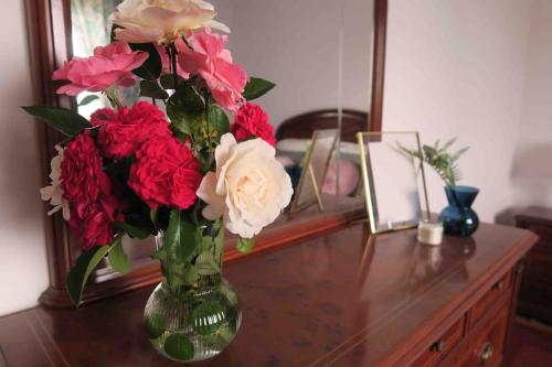 un jarrón lleno de flores rojas y blancas sobre una mesa en Villa Airexe. Chalet con piscina y tenis en la Ribeira Sacra, en Taboada